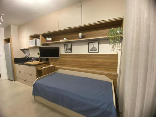 a bedroom with a blue bed and a kitchen at Studio 2 Patteo Helbor - MAIA in Guarulhos