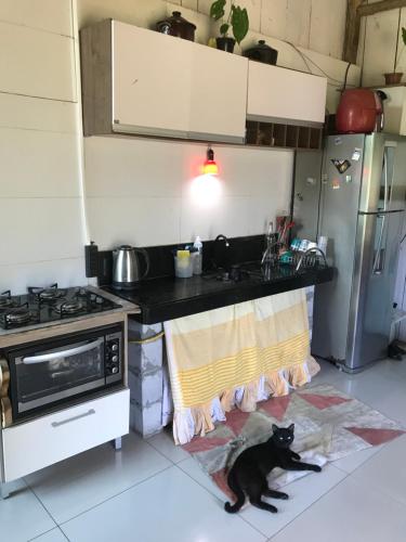 a black cat laying on the floor in a kitchen at Camping Refúgio Shakti II in Florianópolis