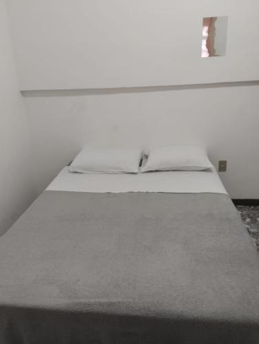 uma cama num quarto branco com em Fine Guest em Belo Horizonte