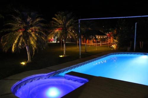 een zwembad verlicht in de nacht met palmbomen bij Quinta Diana in Atlacholoaya
