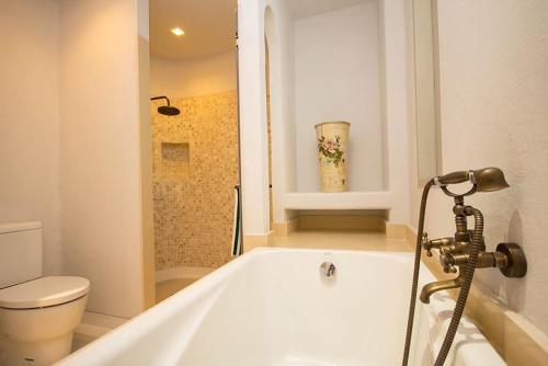 El baño incluye bañera blanca y aseo. en The Chelona en Khao Tao