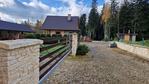 a fence in front of a home with a house at Babiogórskie Domki in Lipnica Wielka