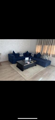 Sala de estar con sofá azul y mesa de centro en Jolie appartement avec terrasse, en Casablanca
