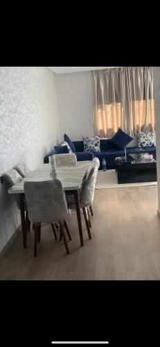 sala de estar con mesa, sillas y sofá en Jolie appartement avec terrasse, en Casablanca