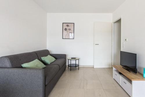 un salon avec un canapé et une télévision dans l'établissement Appartement Juanesco - Welkeys, à Juan-les-Pins