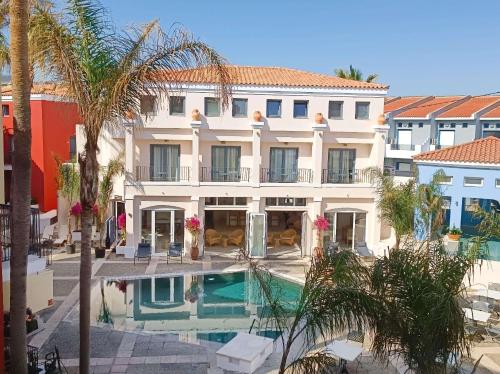 a villa with a swimming pool and palm trees at Grecotel Plaza Beach House in Rethymno Town