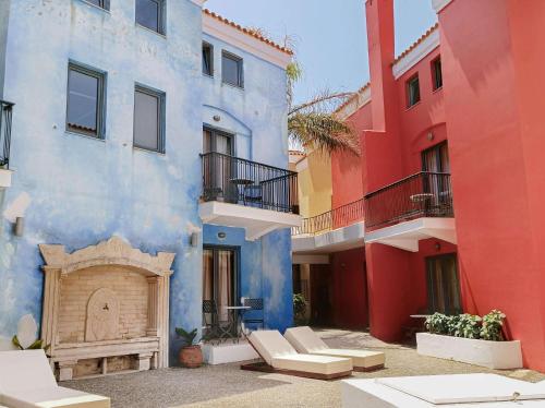 a group of colorful buildings with chairs and a fireplace at Grecotel Plaza Beach House in Rethymno Town