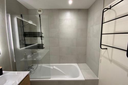 La salle de bains blanche est pourvue d'une baignoire et d'un lavabo. dans l'établissement Aesthetics - 2 bedrooms and secure parking!, à Montpellier