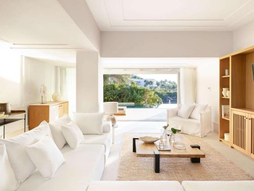 een woonkamer met een witte bank en een tafel bij Corfu Imperial, Grecotel Beach Luxe Resort in Kommeno