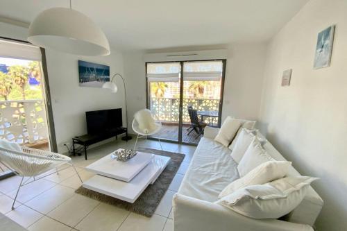 uma sala de estar com um sofá branco e uma mesa em Le Sublime- Vue climatisation et parking ! em Montpellier