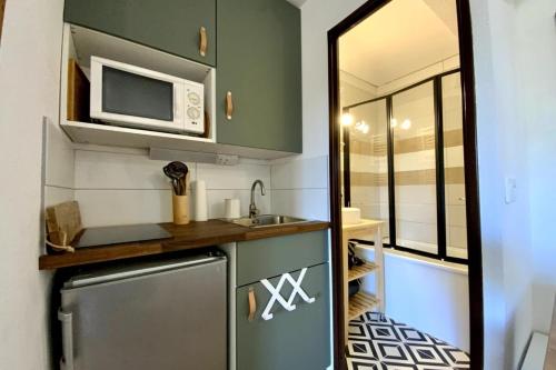 una pequeña cocina con fregadero y microondas en The Edelweiss- Renovated studio for 4 people! en Chamrousse