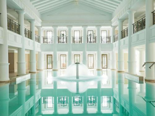 a pool in a building with a table in the water at Grecotel La Riviera & Aqua Park in Loutra Killinis