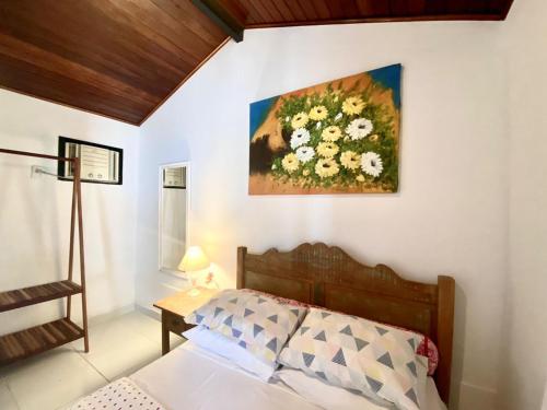 a bedroom with a painting of flowers on the wall at Baluarte Suites in Búzios