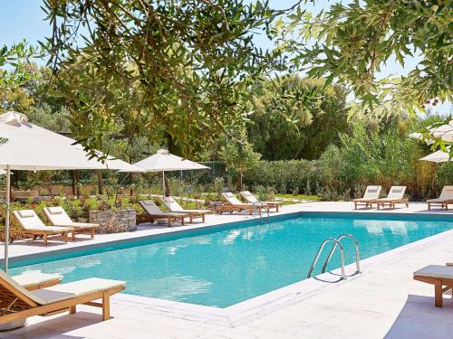 a swimming pool with lounge chairs and umbrellas at Villa Oliva in Adelianos Kampos