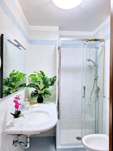 un bagno con lavandino e doccia con piante di Black & White a Cagliari