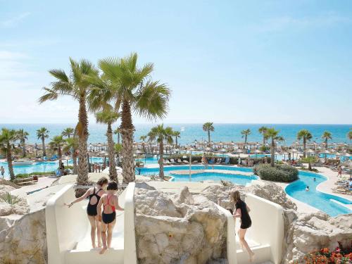 a group of people walking down a slide at a resort at Grecotel Olympia Oasis & Aqua Park in Loutra Killinis