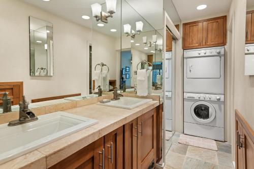 a bathroom with two sinks and a washer and dryer at Spring Street Unit 629, 2BR Condo w/ Mountain Views and Door Step Access to Shops & Restaurants in Aspen
