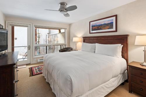a bedroom with a large white bed and a television at Spring Street Unit 629, 2BR Condo w/ Mountain Views and Door Step Access to Shops & Restaurants in Aspen