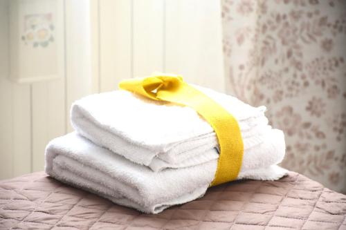 a stack of towels with a yellow ribbon on a bed at La Bouganville in Vitorchiano