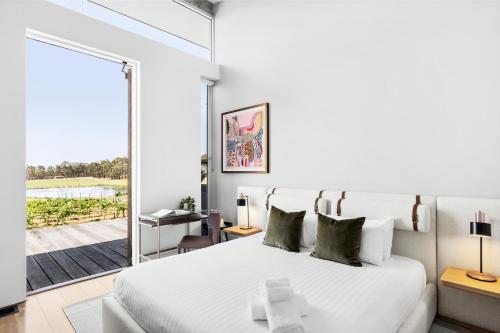 a bedroom with a white bed and a large window at The Longhouse - Suite 1 in Pokolbin