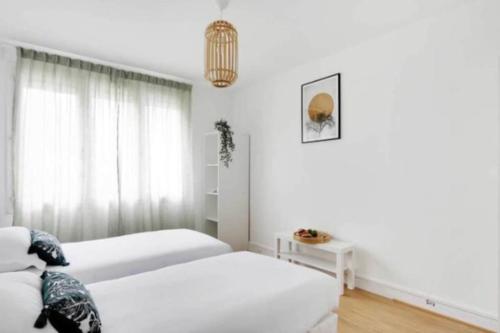 Habitación blanca con 2 camas y lámpara de araña. en Superbe appartement lumineux et calme en Saint-Ouen