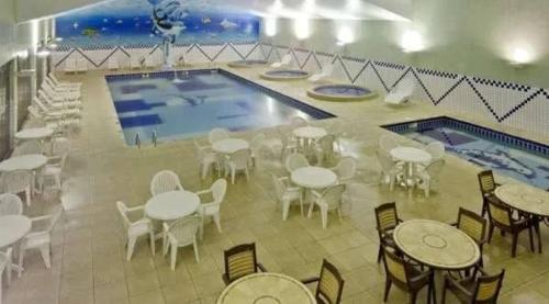 una piscina con mesas y sillas junto a una piscina en Apartamento completo resort, en Represa Capivari