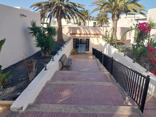 een loopbrug met een bank naast een gebouw bij Casa alisios 71 in Corralejo