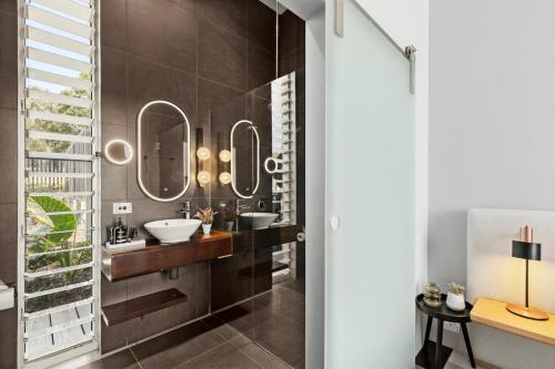 a bathroom with two sinks and two mirrors at The Longhouse - Suite 2 in Pokolbin