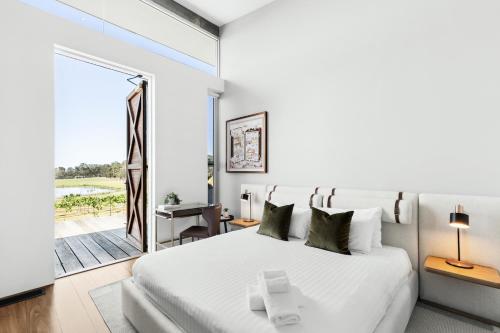 a bedroom with a large white bed and a sliding glass door at The Longhouse - Suite 2 in Pokolbin