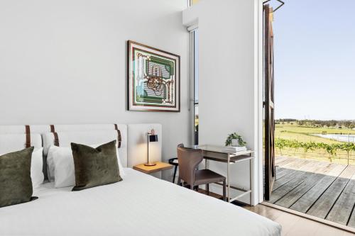 a bedroom with a bed and a desk and a window at The Longhouse - Suite 3 in Pokolbin