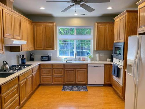 a kitchen with wooden cabinets and a window at Chico Creek House - Hot Tub, Game Room & Fire Pit in Chico