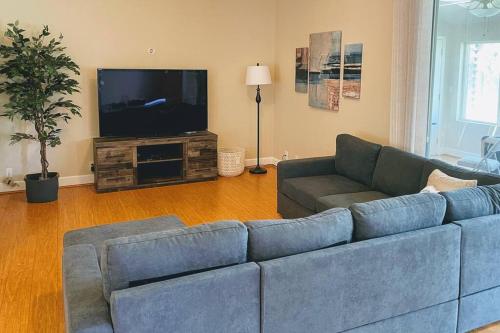 a living room with a blue couch and a flat screen tv at Chico Creek House - Hot Tub, Game Room & Fire Pit in Chico