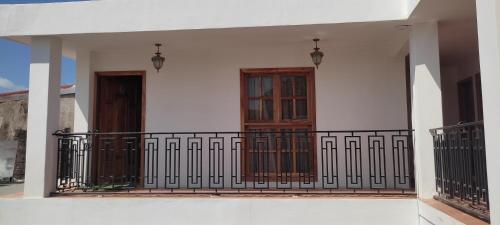 a white house with a balcony with wooden doors at HOSTAL RIVAS INNS in Rivas