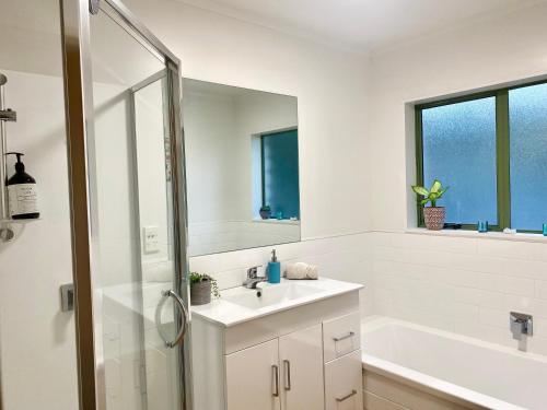 a white bathroom with a sink and a shower at Sanddune Delight in Papamoa