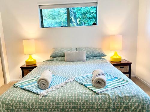 a bedroom with a bed with towels on it at Sanddune Delight in Papamoa