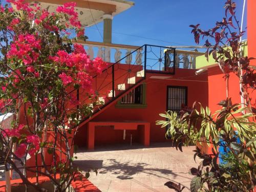 een rood gebouw met een trap en roze bloemen bij La hermosa hotel in Santa Cruz de Barahona