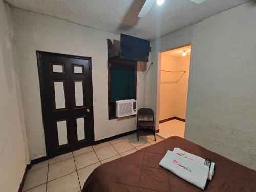 Habitación con cama y puerta con TV en Hotel Chinesca en Mexicali