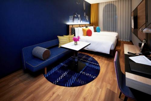 a hotel room with a blue couch and a bed at Citadines Namba Osaka in Osaka