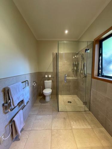 a bathroom with a glass shower and a toilet at Parautane Lodge in Nelson