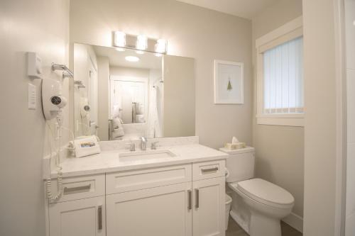 Baño blanco con lavabo y aseo en Ocean Trails Resort, en Parksville