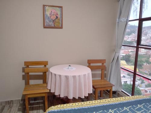 a table and two chairs in a room with a window at Hostal S.Pacha in Sucre