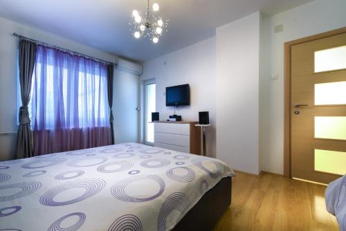 1 dormitorio con 1 cama, TV y puerta en Skopje Luxury Apartments en Skopje