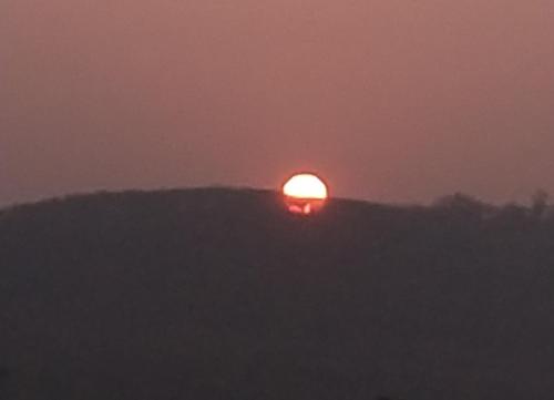 Il sole tramonta sulla cima di una collina di Shivam Residency a Ellora