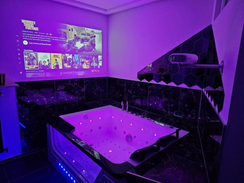 Baño púrpura con bañera con iluminación púrpura en Magnifique Suite Spa Luxembourg, en Differdange
