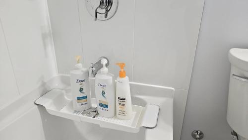 Baño con 3 botellas de artículos de aseo en un estante en Private King Room - Shared Washroom - 5 min to Surrey Fleetwood en Surrey