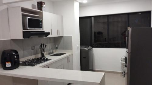 a white kitchen with a refrigerator and a sink at Apartamento Laura María in Medellín