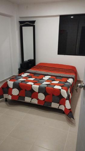a bedroom with a bed with a black and red quilt at Apartamento Laura María in Medellín