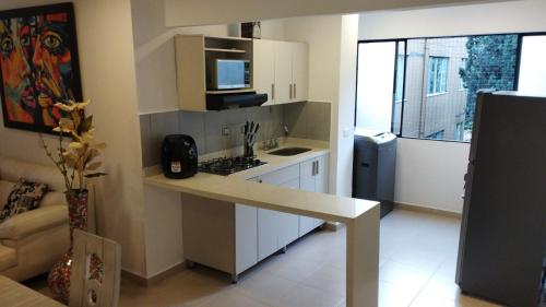 a small kitchen with a stove and a microwave at Apartamento Laura María in Medellín