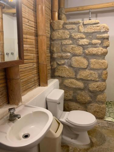 a bathroom with a sink toilet and a stone wall at La Cabaña del Mar Vichayito in Vichayito