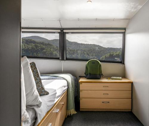 um pequeno quarto com uma cama e uma janela em Milford Sound Overnight Cruise - Fiordland Discovery em Milford Sound
